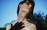 a woman in black leather gloves with a tattoo on her neck