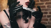 a woman in black latex gloves holding a knife